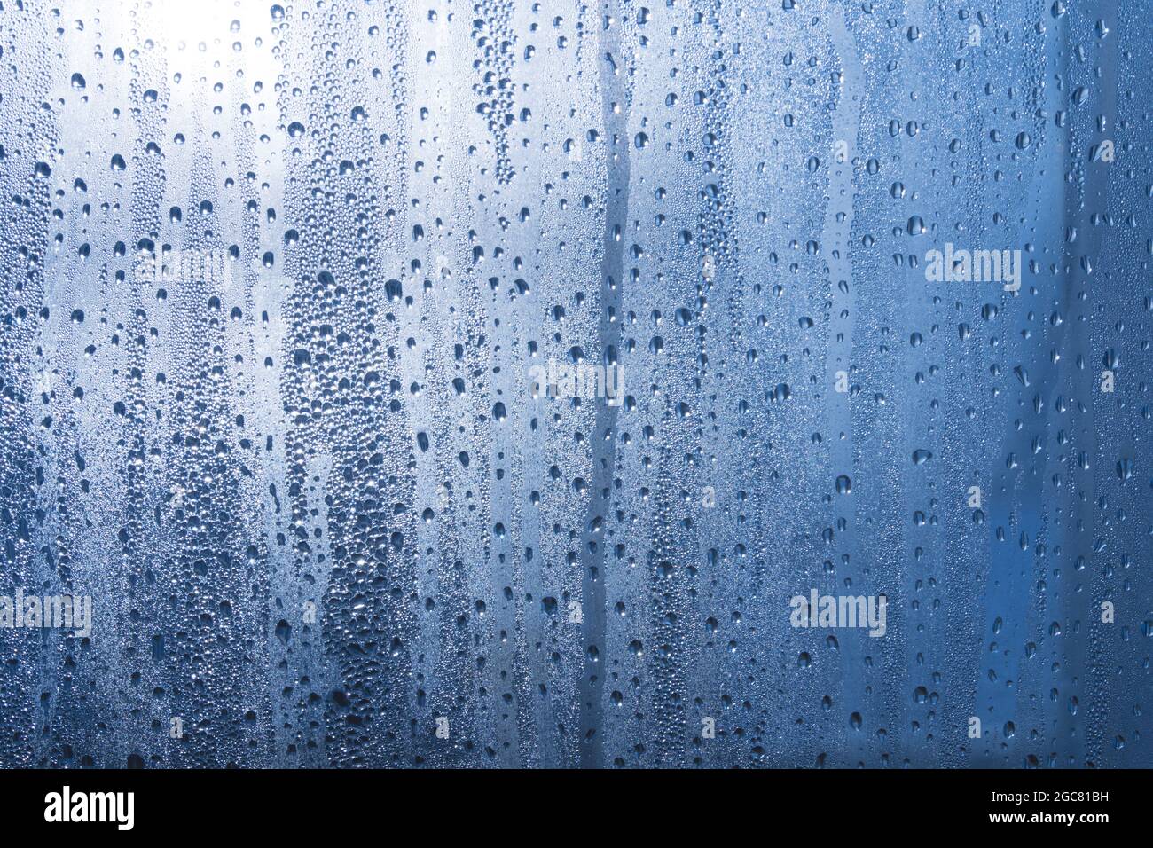 Nach dem Regen ruht ein kleiner Regentropfen auf dem Glas. Regentropfen Auf Dem Glas. Regentropfen auf dem Fenster. Blauton. Abstrakter Hintergrund. Stockfoto