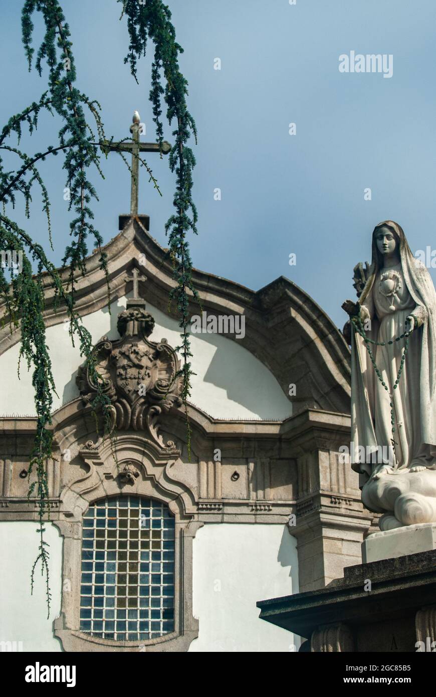 Einfache Kirche Frontbild mit einer Statue und absteigenden Ästen, Kirche des heiligen Antonius in Viana do Castelo, Lärche, Larix Zweige, Vertikal. Stockfoto