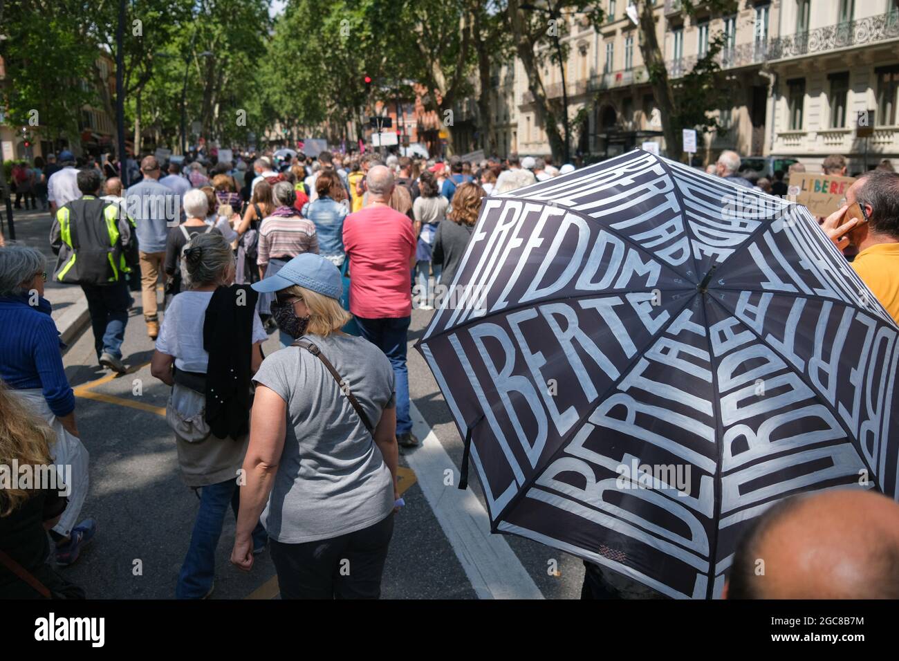 Protestler mit Regenschirm und 'Liberty'-Inschriften in verschiedenen Sprachen. Am 7. August 2021 widersetzten sich mehrere tausend Menschen dem prefekturalen Demonstragungsverbot, das in den Straßen von Toulouse (Frankreich) zu sehen war. Mit dem Wort "Freiheit" und Anti-Macron-Parolen marschierten die Demonstranten auf den Boulevards des Stadtzentrums und protestierten damit gegen den Sanitary Pass. Foto von Patrick Batard/ABACAPRESS.COM Stockfoto