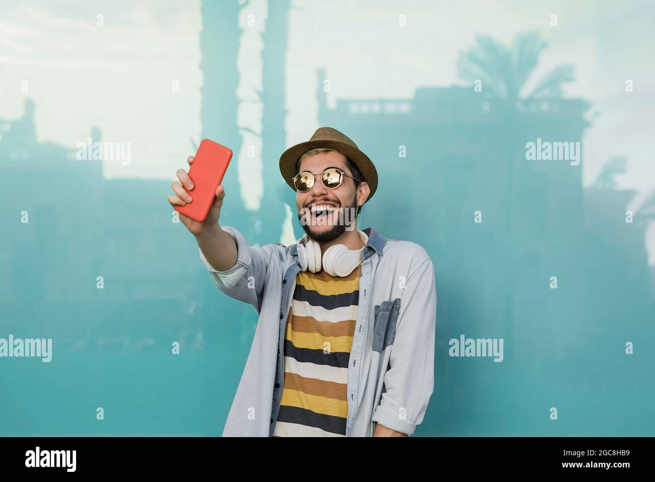 Junger Hipster-Mann macht ein Selfie mit Handy im Freien mit blauem Hintergrund - Fokus auf Gesicht Stockfoto