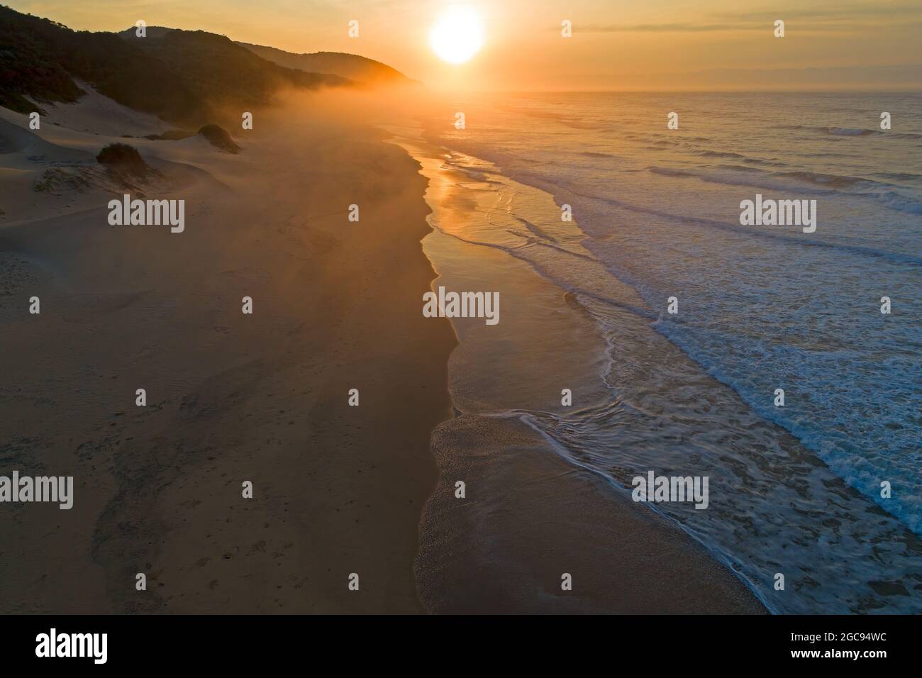 Malerischer Sandstrand bei Sonnenaufgang mit warmen Farben von der frühen Morgensonne, Südafrika Stockfoto