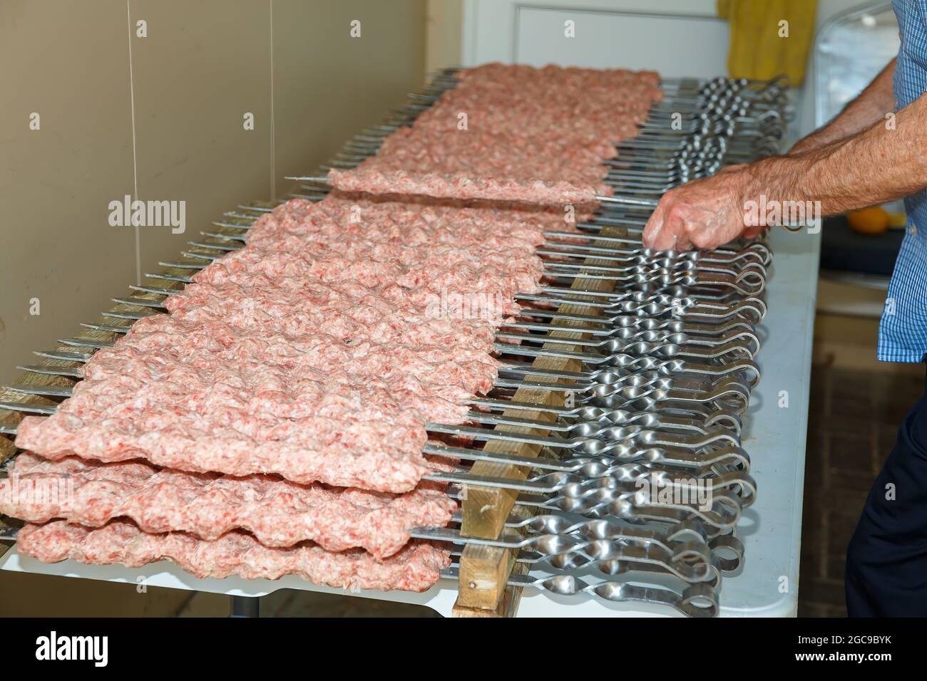 Rohe Würstchen vor dem Grillieren auf Spieße aufgereiht Stockfoto