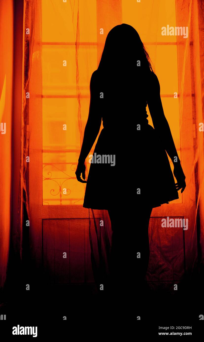 Silhouette einer Frau in einem Kleid vor der Balkontür Stockfoto
