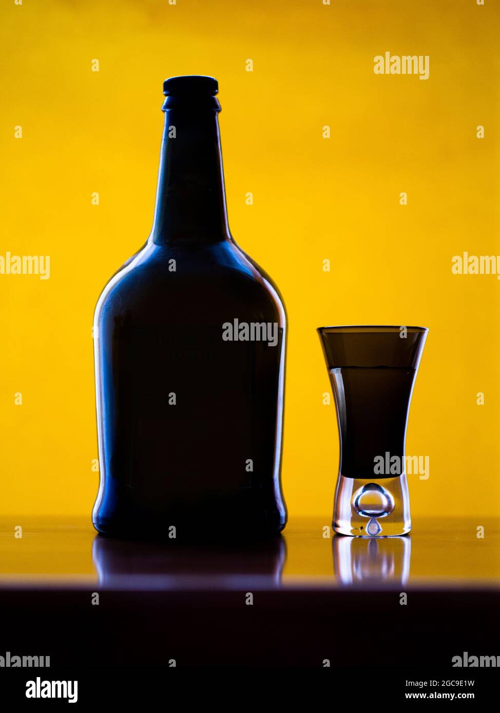 Flasche und ein Glas vor gelbem Hintergrund Stockfoto