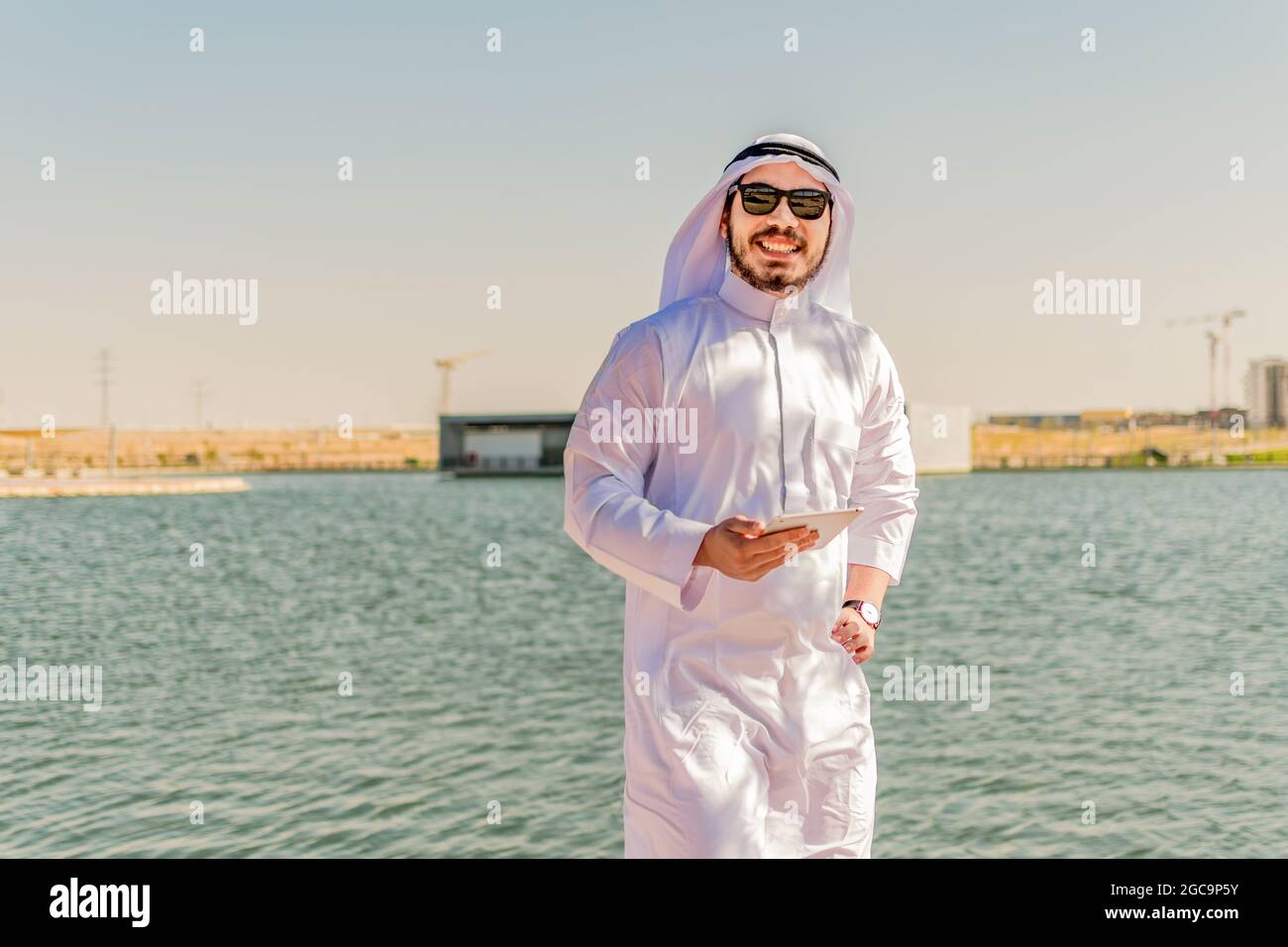Glücklicher muslimischer Mann in traditioneller Kleidung, lächelnd an der Kamera, im Nahen Osten. Stockfoto