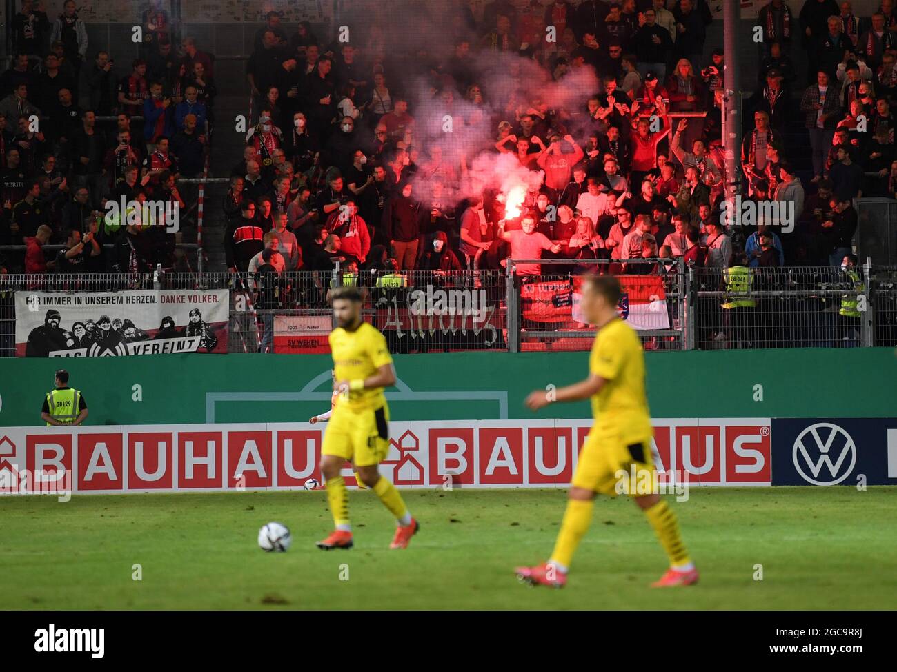 07. August 2021, Hessen, Wiesbaden: Fußball: DFB-Pokal, SV Wehen Wiesbaden - Borussia Dortmund, 1. Runde in der Brita Arena. Wiesbadener Lüfter brennen Pyrotechnik im Lüfterblock. (Wichtiger Hinweis: Der DFB untersagt die Verwendung von Sequenzbildern im Internet und in Online-Medien während des Spiels (einschließlich Halbzeit). Sperrfrist! Der DFB erlaubt die Veröffentlichung und Weiterverwendung der Bilder auf mobilen Endgeräten (insbesondere MMS) und über DVB-H und DMB erst nach Ende des Spiels). Foto: Arne Dedert/dpa - WICHTIGER HINWEIS: Gemäß den Vorschriften der DFL Deutsche Fußball Liga an Stockfoto
