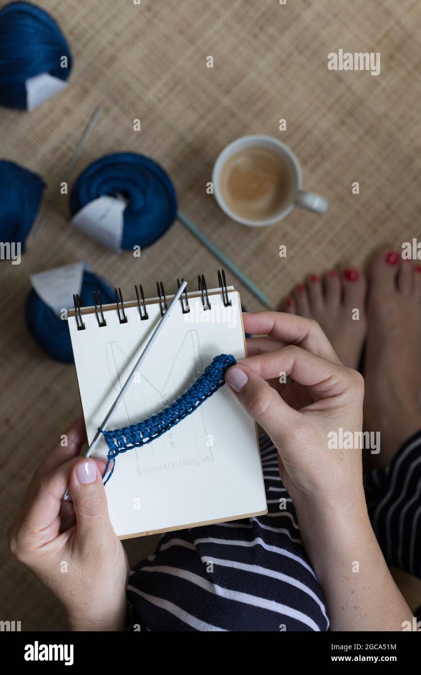 Frau mit einem kleinen blauen Leinenstich über einem handgezeichneten Motiv. Stockfoto