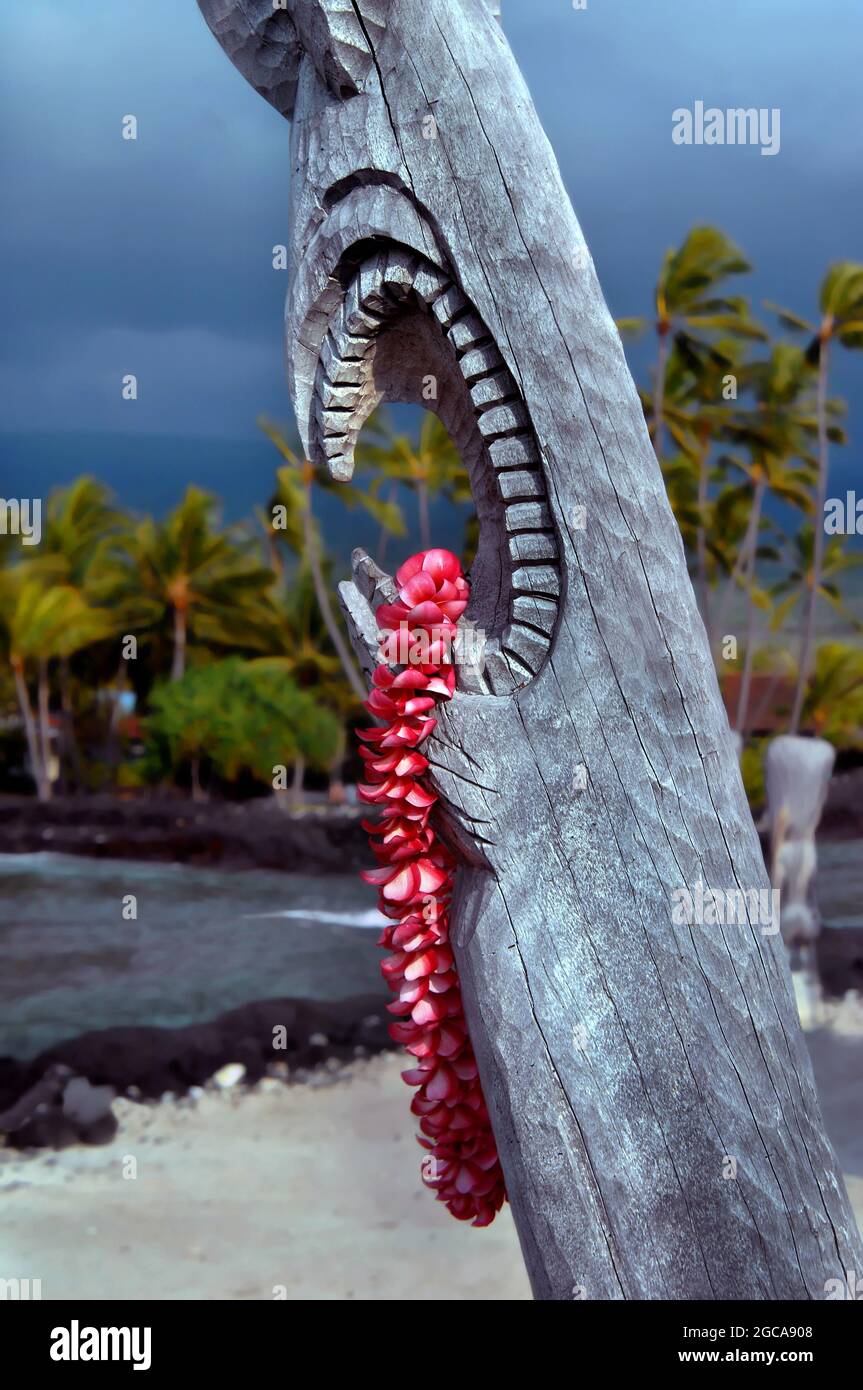 Wunderschöne rosa Plumeria lei hängt von der offenen Mündung eines hawaiianischen Tiki im Puuhonua o Honaunau National Historical Park auf der Big Island von Hawaii. Stockfoto