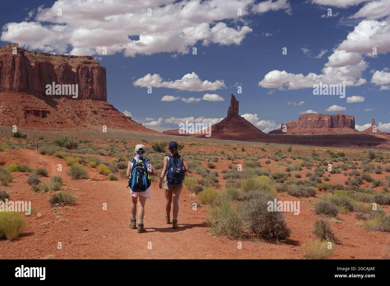 Zwei Personen wandern auf dem Wildcat Trail im Monument Valley Navajo Tribal Park, USA. Ein heißer augusttag mit blauem Himmel und Sandsteinfelsen, Buttes und Pinna Stockfoto