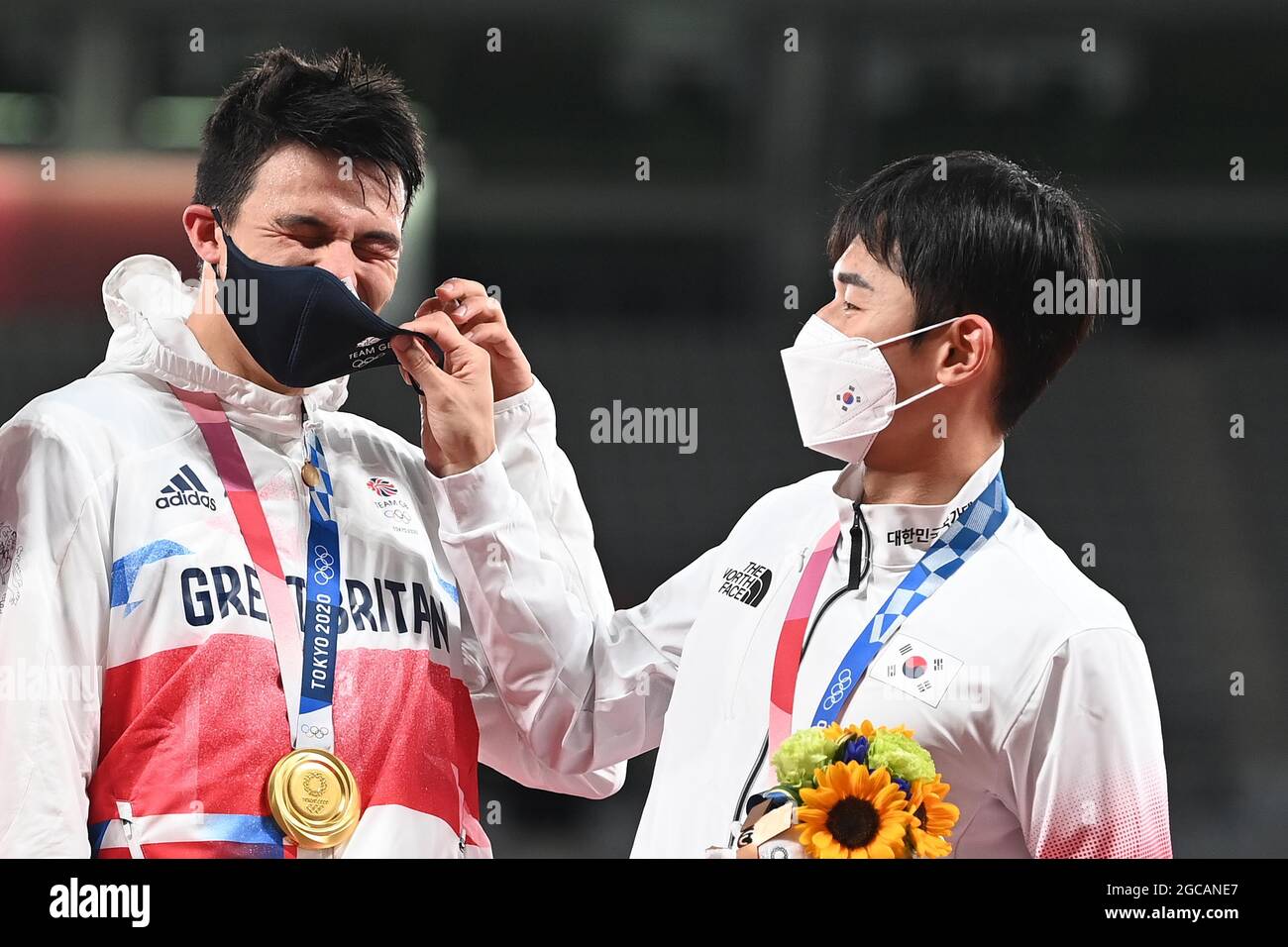 Tokio, Japan. August 2021. Moderner Fünfkampf. Herren individuell. Tokyo Stadium. 376-3. Nishimachi. Chofu-shi. Tokio. Joseph Choong (GBR) feiert mit seiner GOLDMEDAILLE und hat Probleme mit seiner Maske, also HILFT BRONZEMEDAILLENGEWINNERIN Woongtae Jun (Kor). Kredit Garry Bowden/Sport in Pictures/Alamy live News Kredit: Sport in Pictures/Alamy Live News Stockfoto