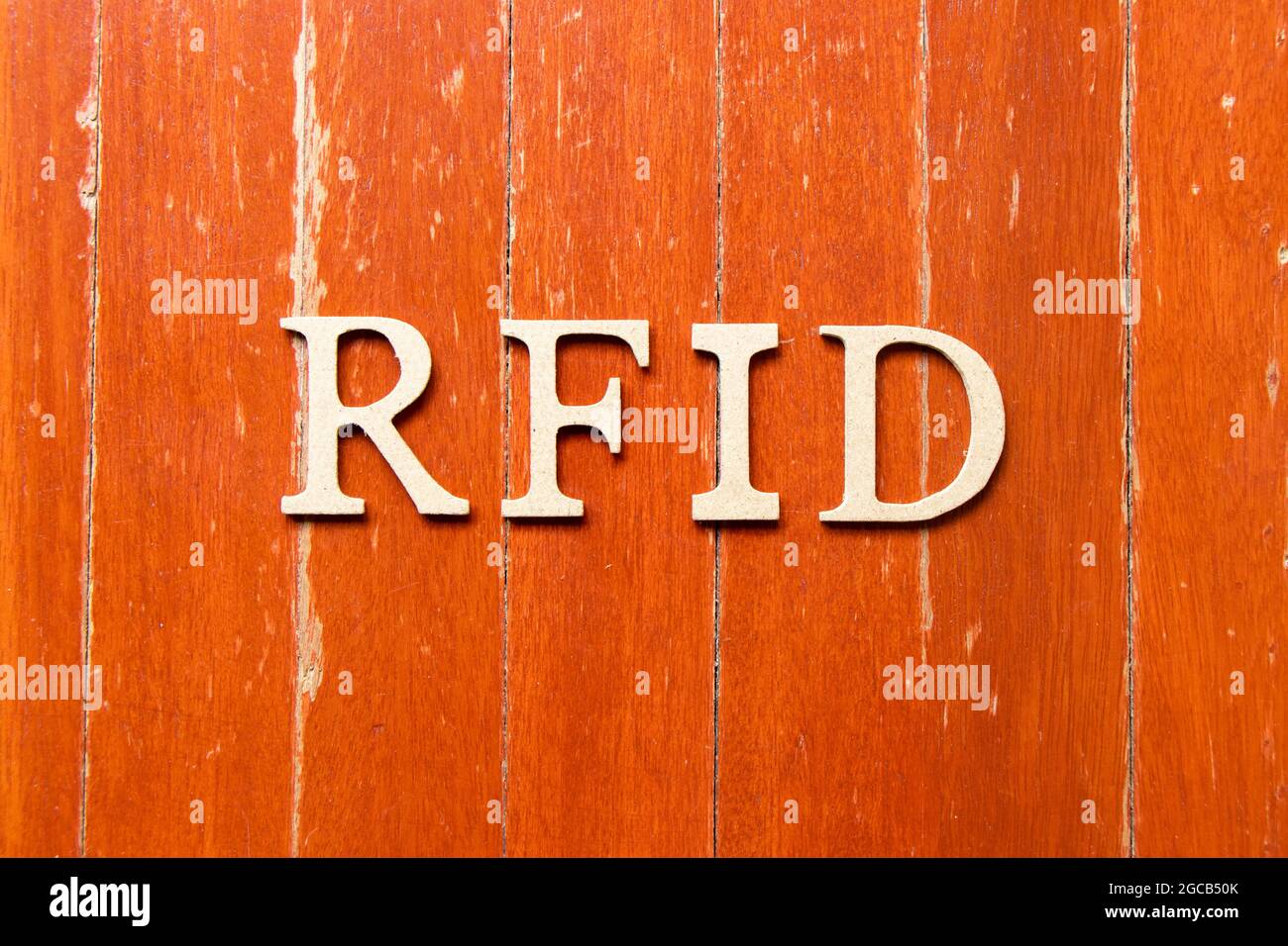 Buchstabenbuchstabe im Wort RFID (Abkürzung für Radio-frequency Identification) auf altem roten Hintergrund der Holzplatte Stockfoto