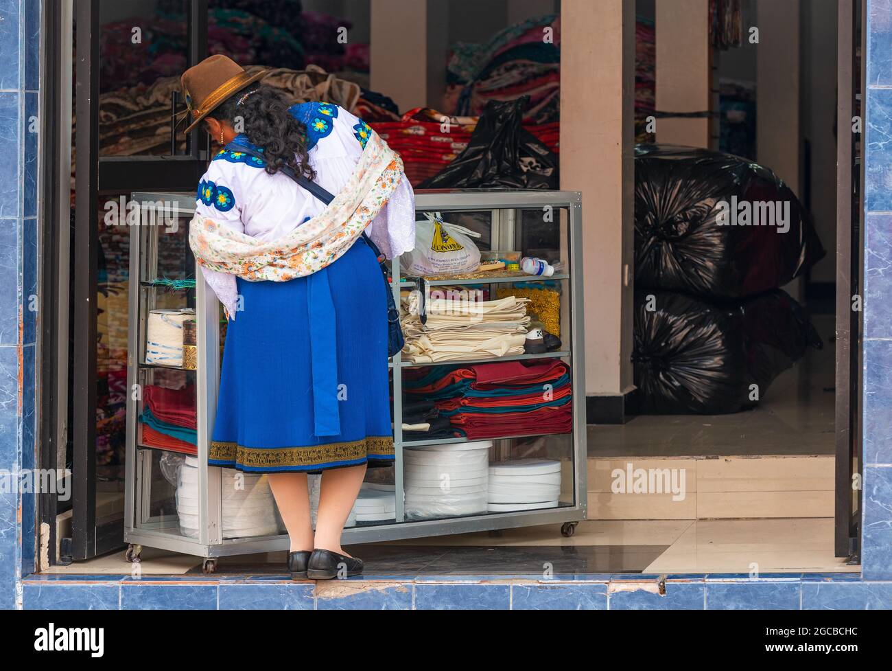 Ecuadorianische indigene Otavalo-Frau beim traditionellen Bekleidungskauf im Textilwarengeschäft, Otavalo, Ecuador. Stockfoto