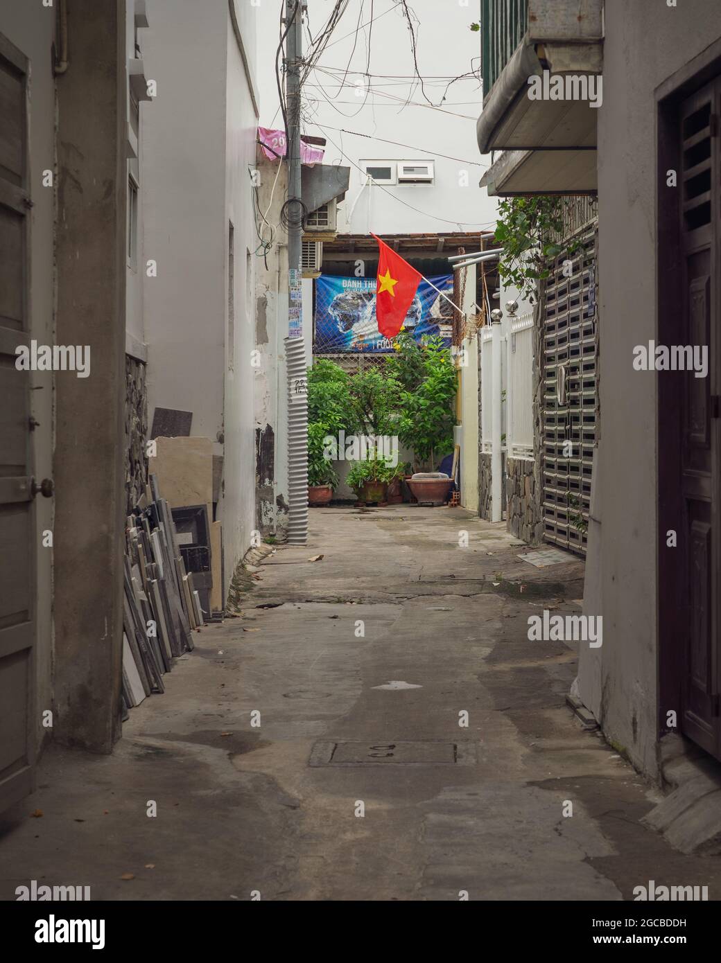 Vietnamesische enge Wohnstraße mit einer Nationalflagge am Ende. Nha Trang, Vietnam: 2020-10-13 Stockfoto
