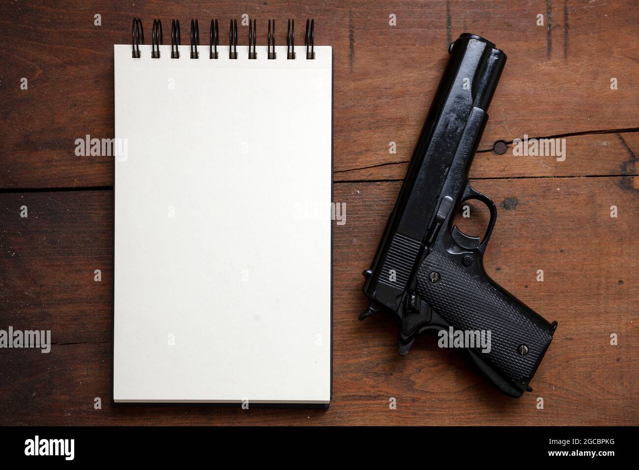 Selbstmordnotiz, Morduntersuchung. Leerer Notizblock und Pistolenpistole auf Holztischhintergrund, Draufsicht. Kopieren Sie die Raumvorlage Stockfoto