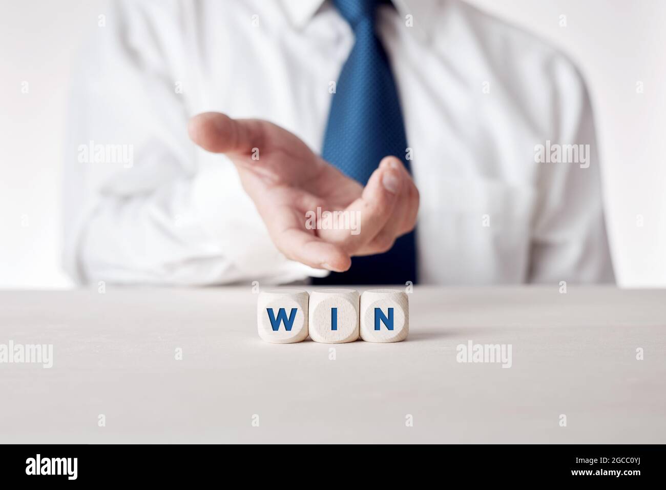 Hand eines Geschäftsmannes, der die Holzwürfel mit dem Wort Win präsentiert. Erfolg- oder Win-Win-Strategie im Geschäftskonzept. Stockfoto