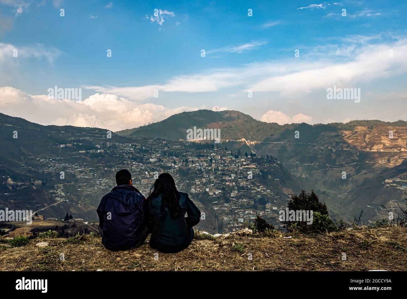 Das Paar, das am oberen Rand des Berges mit überfüllter Stadtstruktur und erstaunlicher Abendhimmel sitzt, wird bei der Bombe arunachal pradesh india aufgenommen. Stockfoto