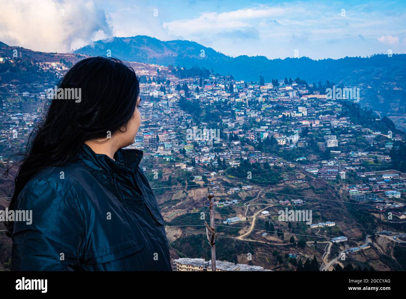 Isoliertes Mädchen auf der Bergspitze mit überfüllter Stadtstruktur und erstaunlicher Himmel am Abend das Bild wird bei der Bombe arunachal pradesh india aufgenommen. Stockfoto