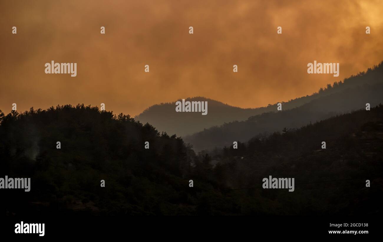 Nachdem das Kraftwerk Kemerkoy durch einen Waldbrand verbrannt wurde, erreichten Blasen auch das Wärmekraftwerk Yenikoy in Milas, in der südwestlichen Provinz Mugla der Türkei. Dieser Brand wurde früh von Feuerwehrmannschaften gelöscht. Feuerwehrmänner und städtische Teams in der ganzen Türkei haben in Feslegen, Bay?r und anderen Dörfern, die von massiven Waldbränden betroffen waren, weiterhin aus der Luft und dem Boden gelöscht. Waldarbeiter wurden Bäume geschnitten, um ein mögliches Waldbrand in der Zone des thermischen Kraftwerks in der Nähe der Straße zu verhindern. Einige Nichtregierungsorganisationen und Gemeinden haben Lebensmittel und Wat verteilt Stockfoto
