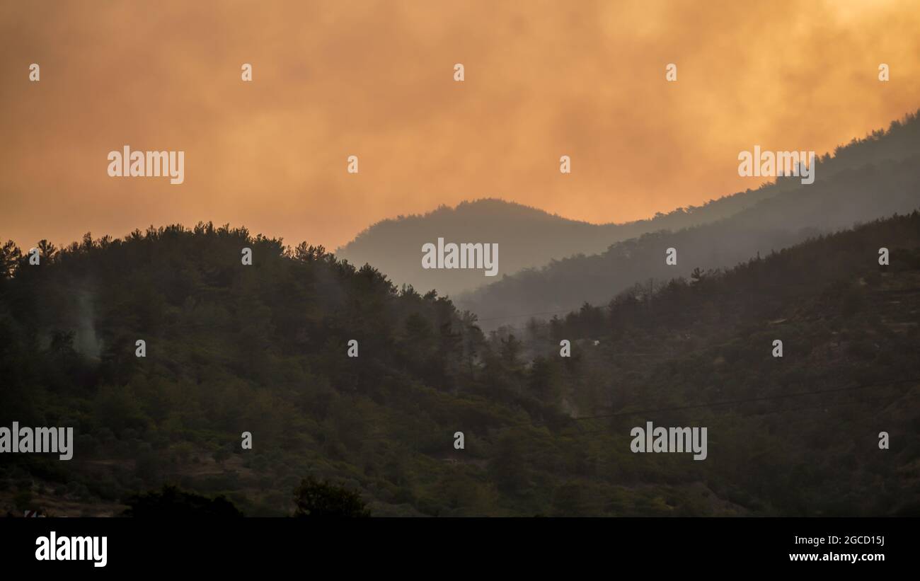 Nachdem das Kraftwerk Kemerkoy durch einen Waldbrand verbrannt wurde, erreichten Blasen auch das Wärmekraftwerk Yenikoy in Milas, in der südwestlichen Provinz Mugla der Türkei. Dieser Brand wurde früh von Feuerwehrmannschaften gelöscht. Feuerwehrmänner und städtische Teams in der ganzen Türkei haben in Feslegen, Bay?r und anderen Dörfern, die von massiven Waldbränden betroffen waren, weiterhin aus der Luft und dem Boden gelöscht. Waldarbeiter wurden Bäume geschnitten, um ein mögliches Waldbrand in der Zone des thermischen Kraftwerks in der Nähe der Straße zu verhindern. Einige Nichtregierungsorganisationen und Gemeinden haben Lebensmittel und Wat verteilt Stockfoto
