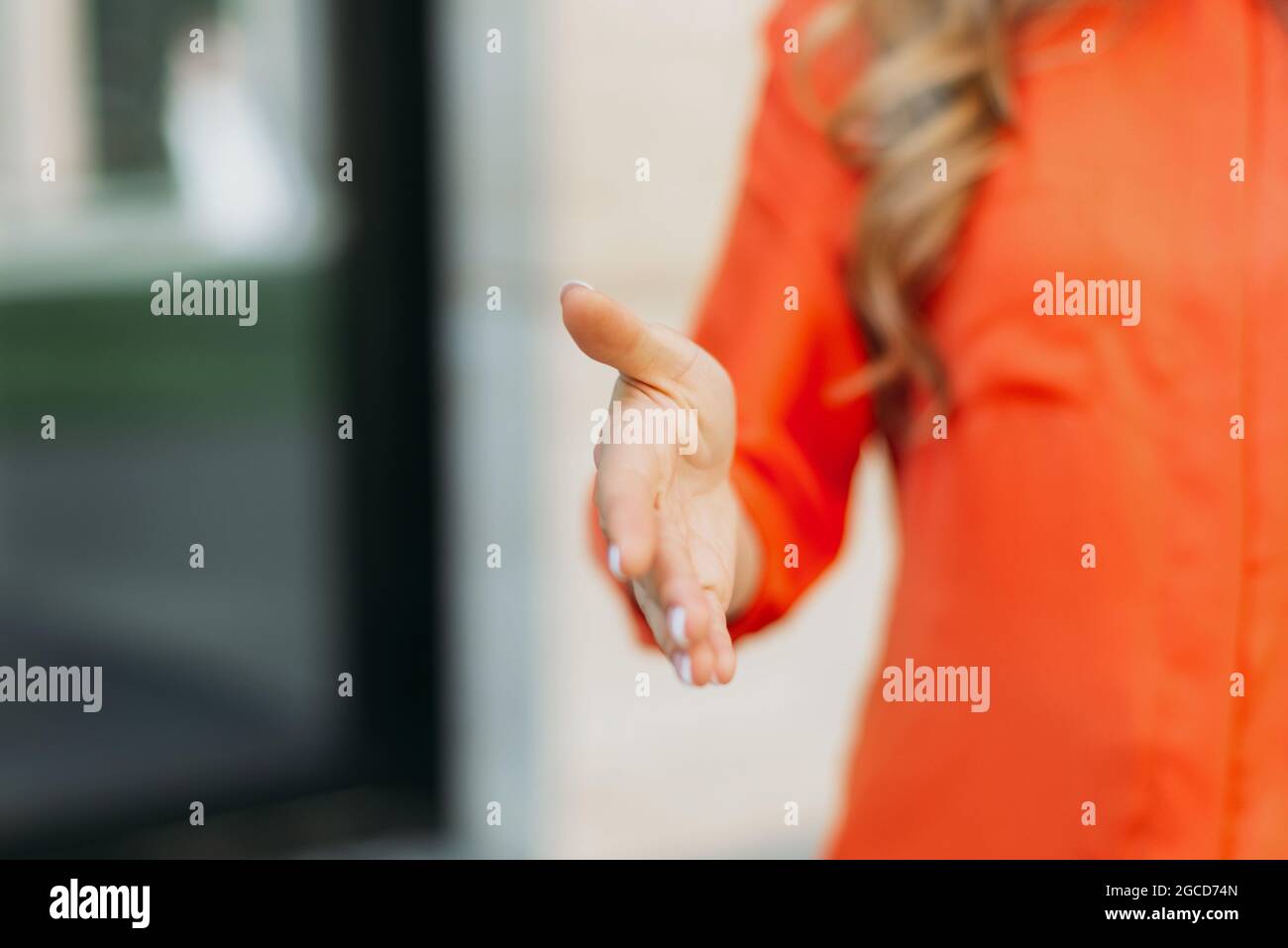 Die kaukasische Frau streckt ihre Hand aus, um sie zu begrüßen oder zu grüßen Stockfoto
