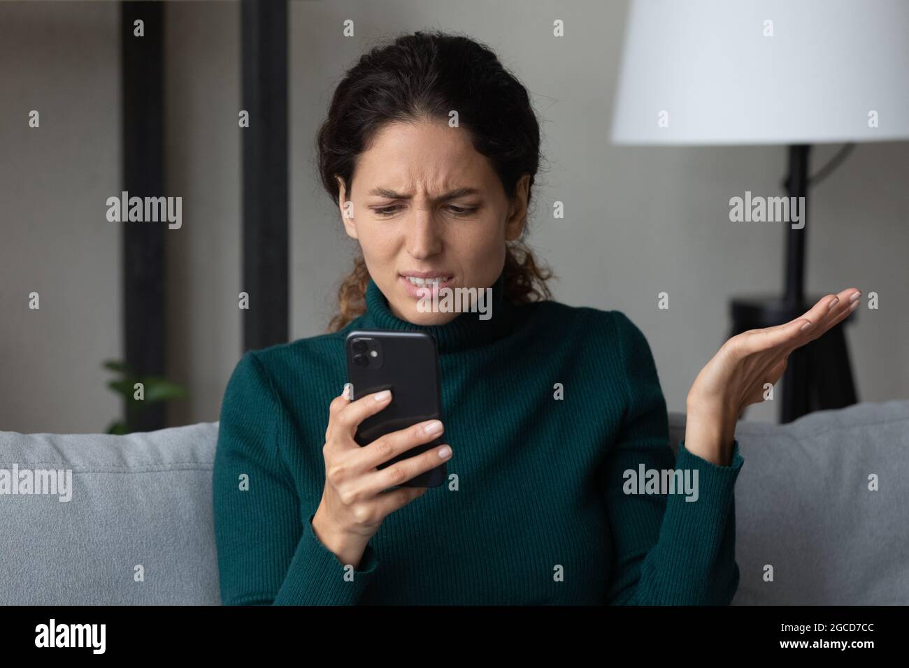 Nahaufnahme wütende unzufriedene Frau, die auf den Telefonbildschirm schaut Stockfoto