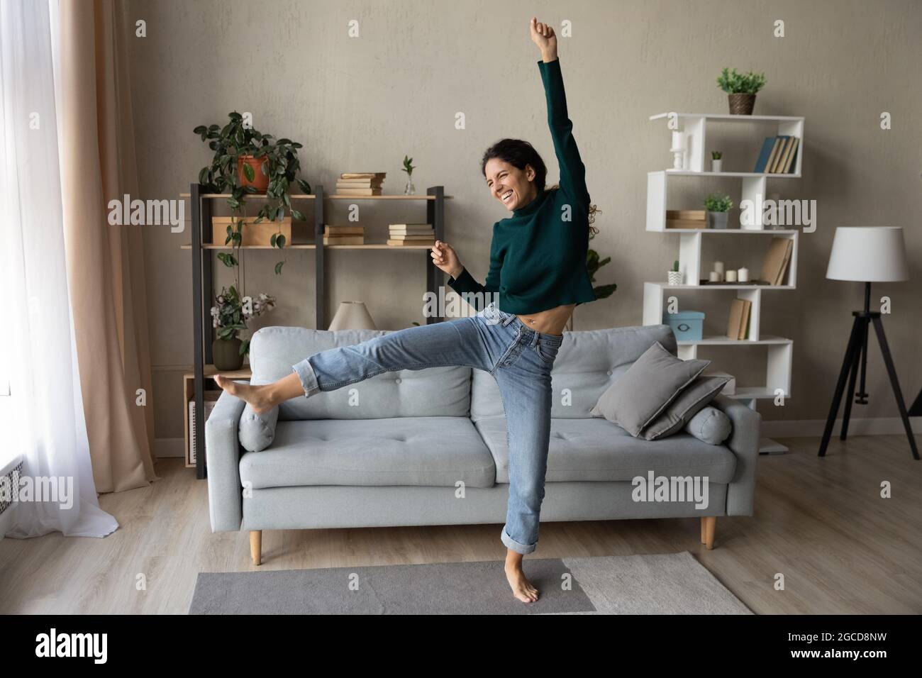 Überfröhliche Frau, die im gemütlichen Wohnzimmer tanzt und den Erfolg feiert Stockfoto