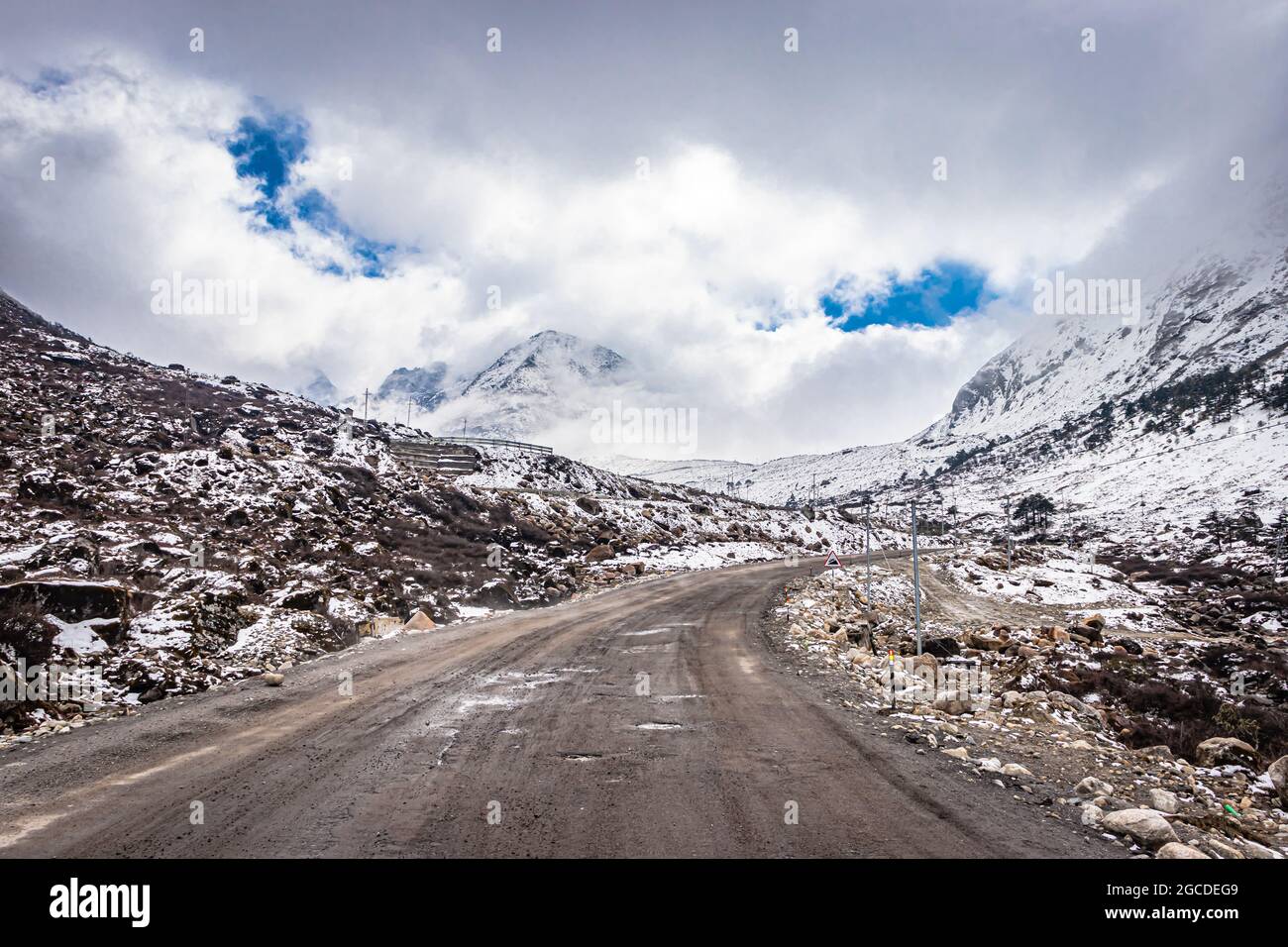 Isolierte asphaltierte Straße mit schneebedeckter Bergkulisse und erstaunlichem Himmel am Morgen Bild wird am sela-Pass tawang arunachal pradesh aufgenommen. Stockfoto