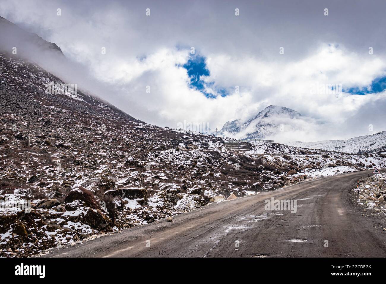 Isolierte asphaltierte Straße mit schneebedeckter Bergkulisse und erstaunlichem Himmel am Morgen Bild wird am sela-Pass tawang arunachal pradesh aufgenommen. Stockfoto