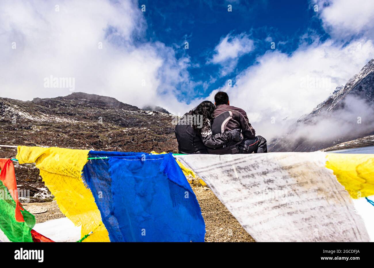 Isoliertes junges Paar, das am Berggipfel mit buddhistischen Flaggen sitzt, am Tag wurde das Bild am sela-Pass tawang arunachal pradesh india aufgenommen. Stockfoto