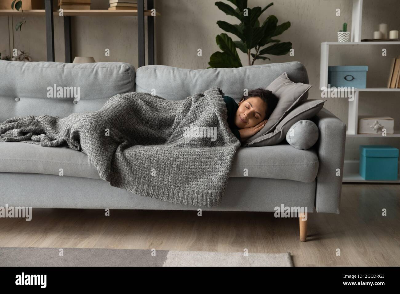 Die ganze Länge friedliche Frau ruht unter einer warmen Decke auf der Couch Stockfoto