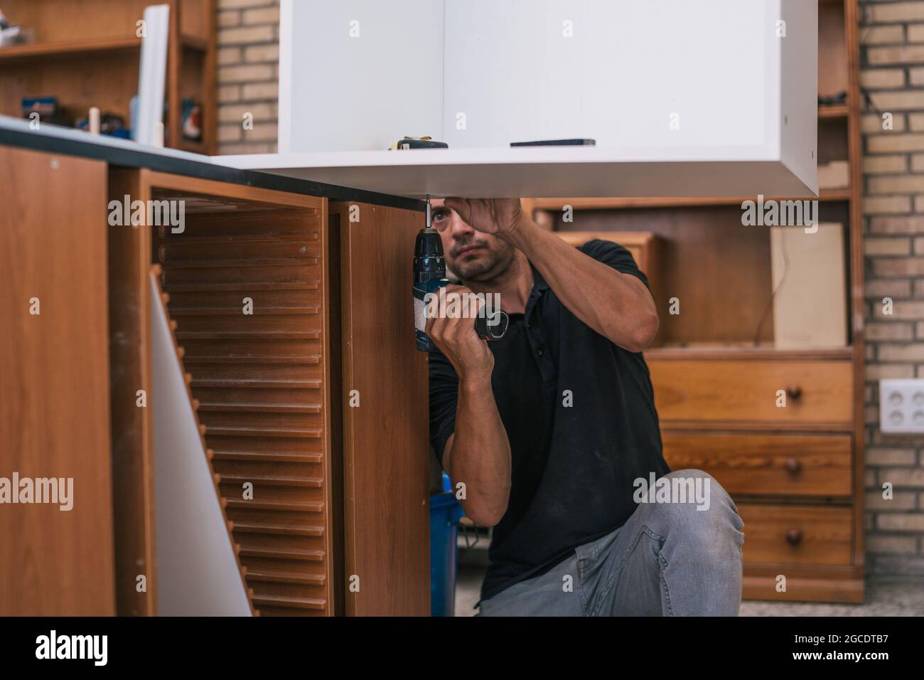 Arbeiter bohrt ein Loch unter einem Brett in einer Werkstatt. Stockfoto