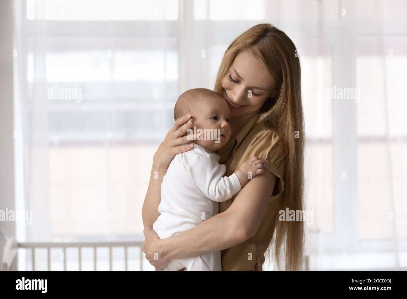 Lächelnde junge Mutter halten in den Armen Baby Kleinkind Stockfoto