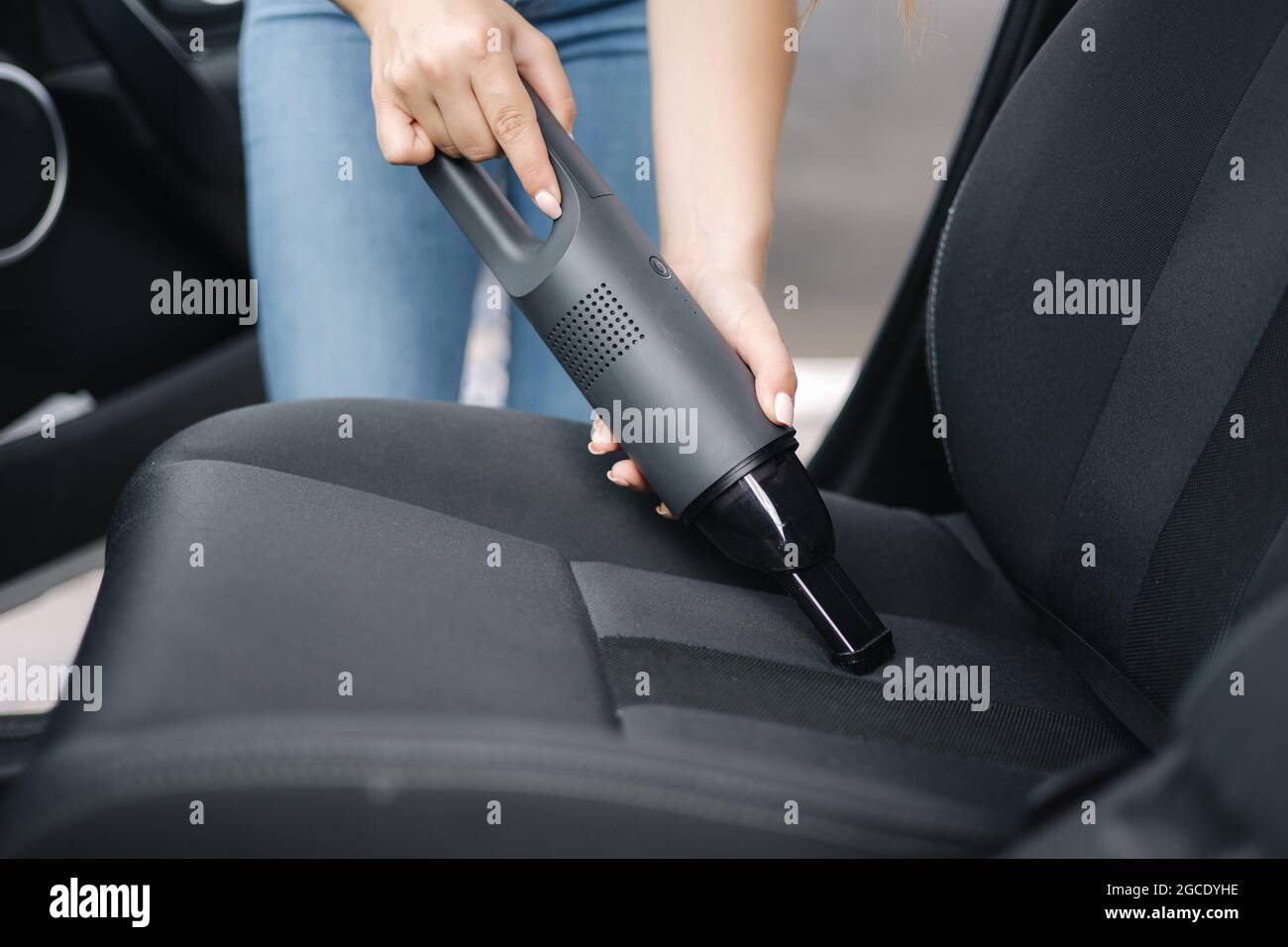 Nahaufnahme einer Frau, die in ihrem Auto einen tragbaren Staubsauger  verwendet. Elektrischer Staubsauger in der Hand einer Frau Reinigen Sie das  Auto im Inneren von Staub Stockfotografie - Alamy