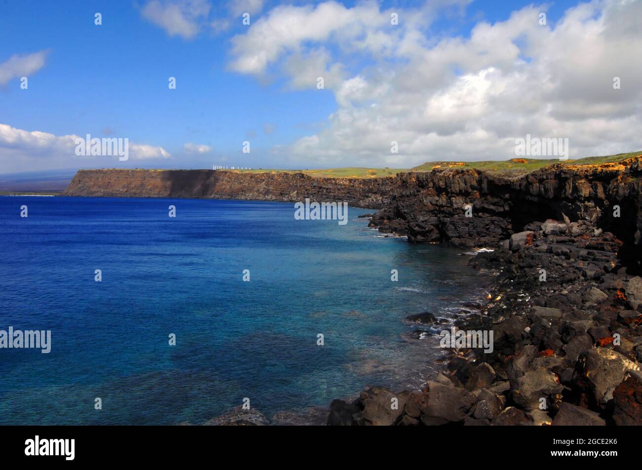 Wunderschön, South Point, hat zerklüftete steile Klippen, die von lebhaftem blauen Wasser umgeben sind. Windturbinen säumen die Klippe. Stockfoto