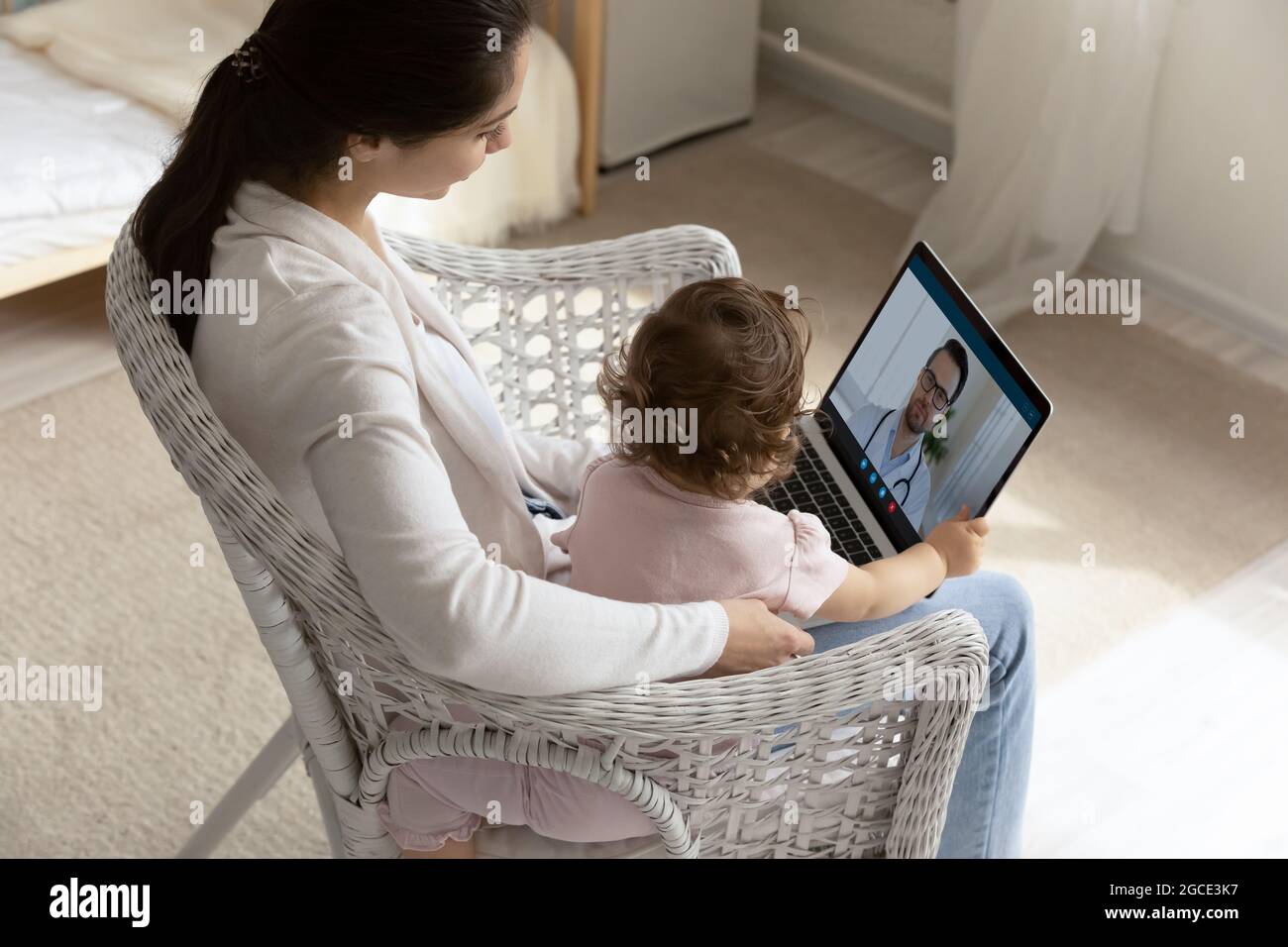 Junge Mutter mit Baby Tochter sprechen Sie mit Arzt online Stockfoto