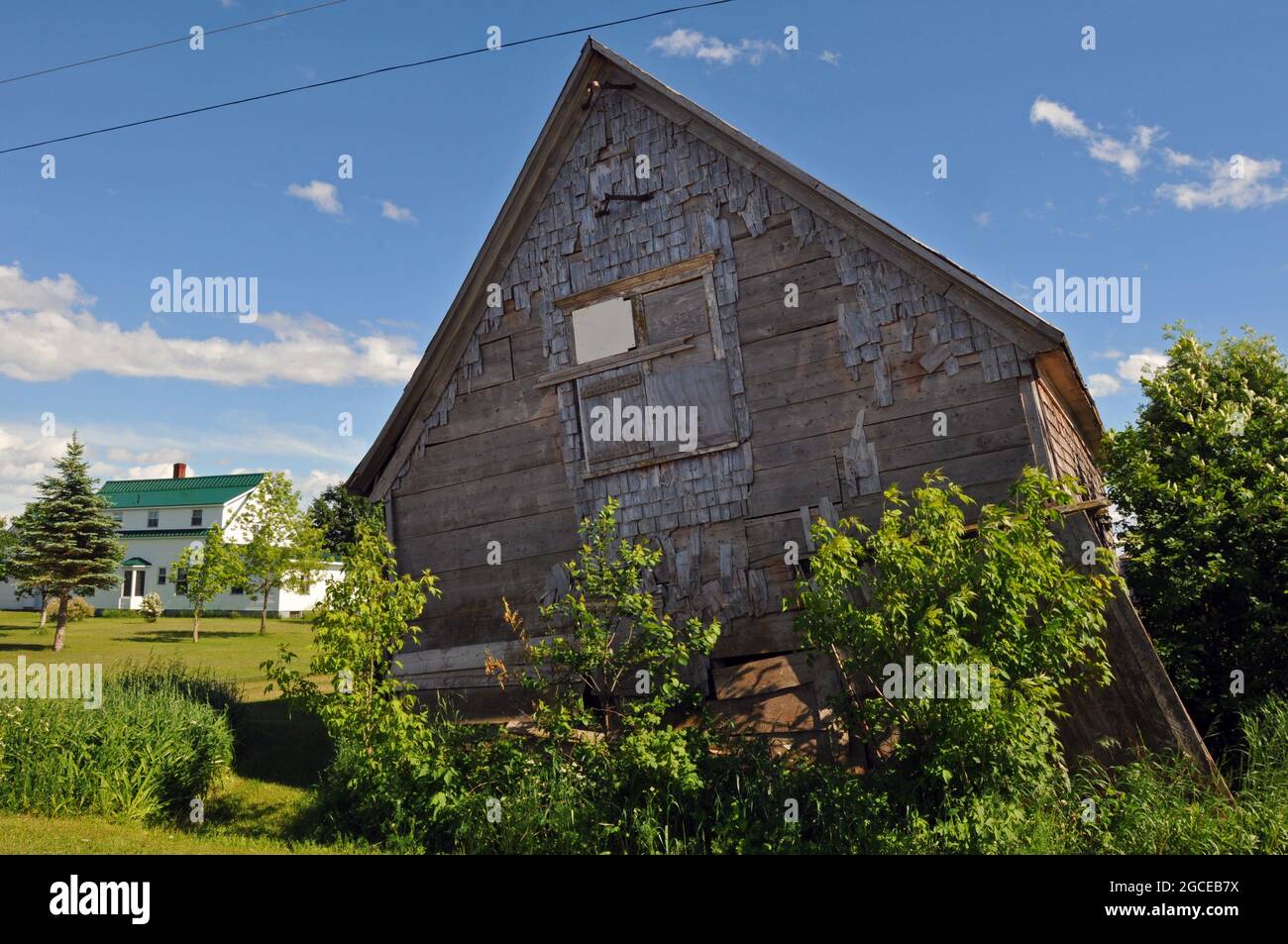 Ein altes Holzgebäude lehnt sich am Straßenrand in der Nähe von West Cape, Prince Edward Island. Stockfoto