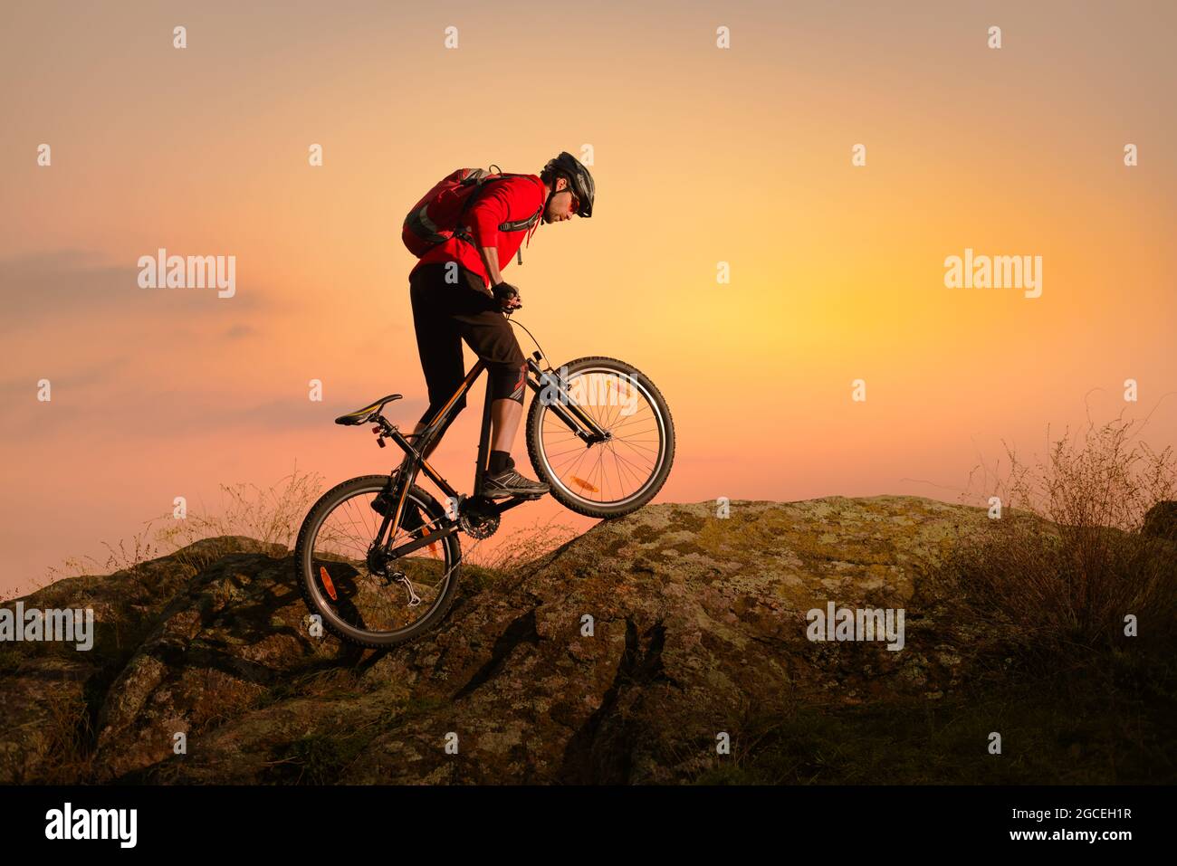 Radler in Red Riding Bike auf dem Spring Rocky Trail bei Sonnenuntergang. Extreme Sport und Enduro Biking Konzept. Stockfoto