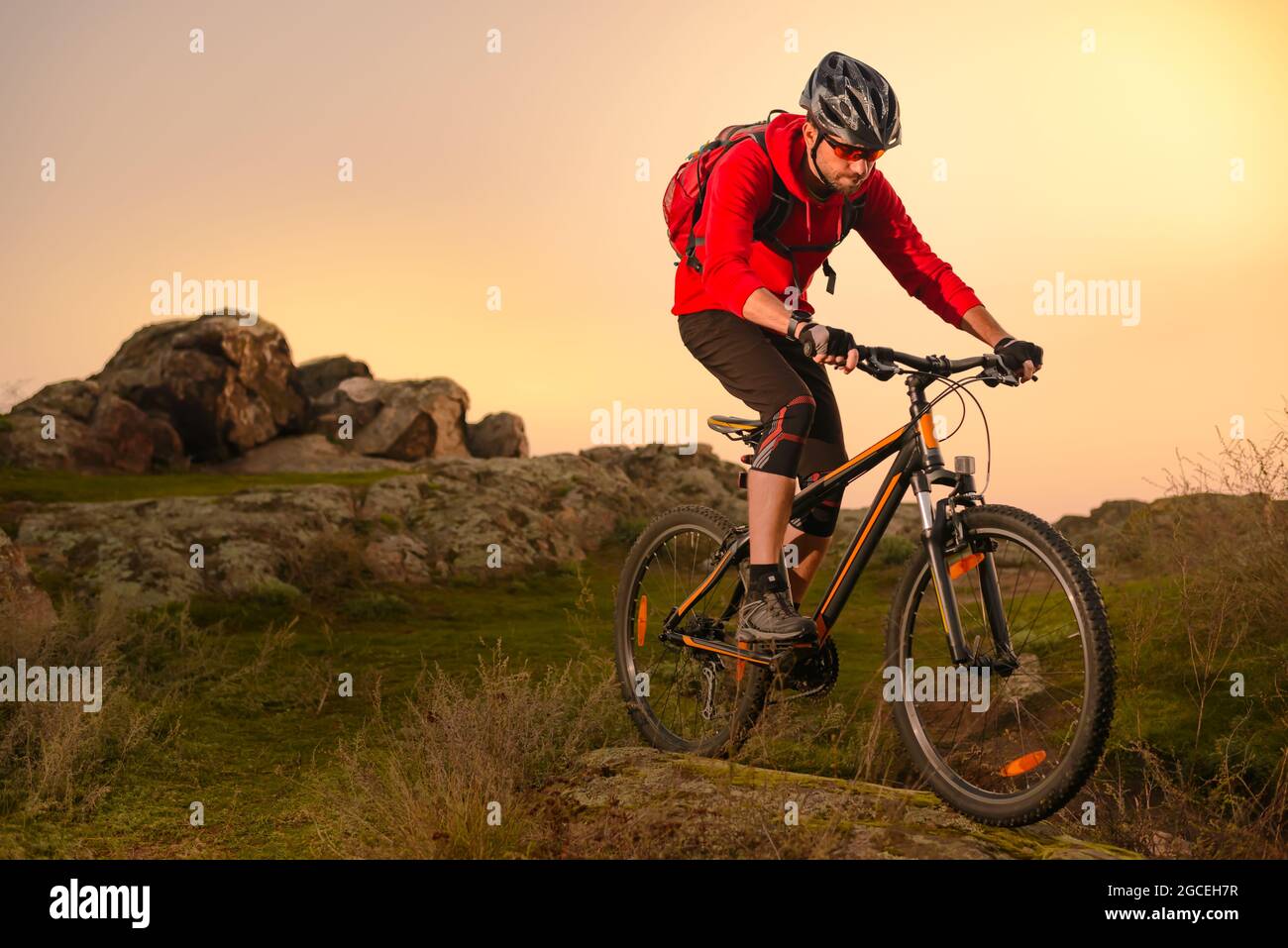 Radler in Red Riding Bike auf dem Spring Rocky Trail bei Sonnenuntergang. Extreme Sport und Enduro Biking Konzept. Stockfoto