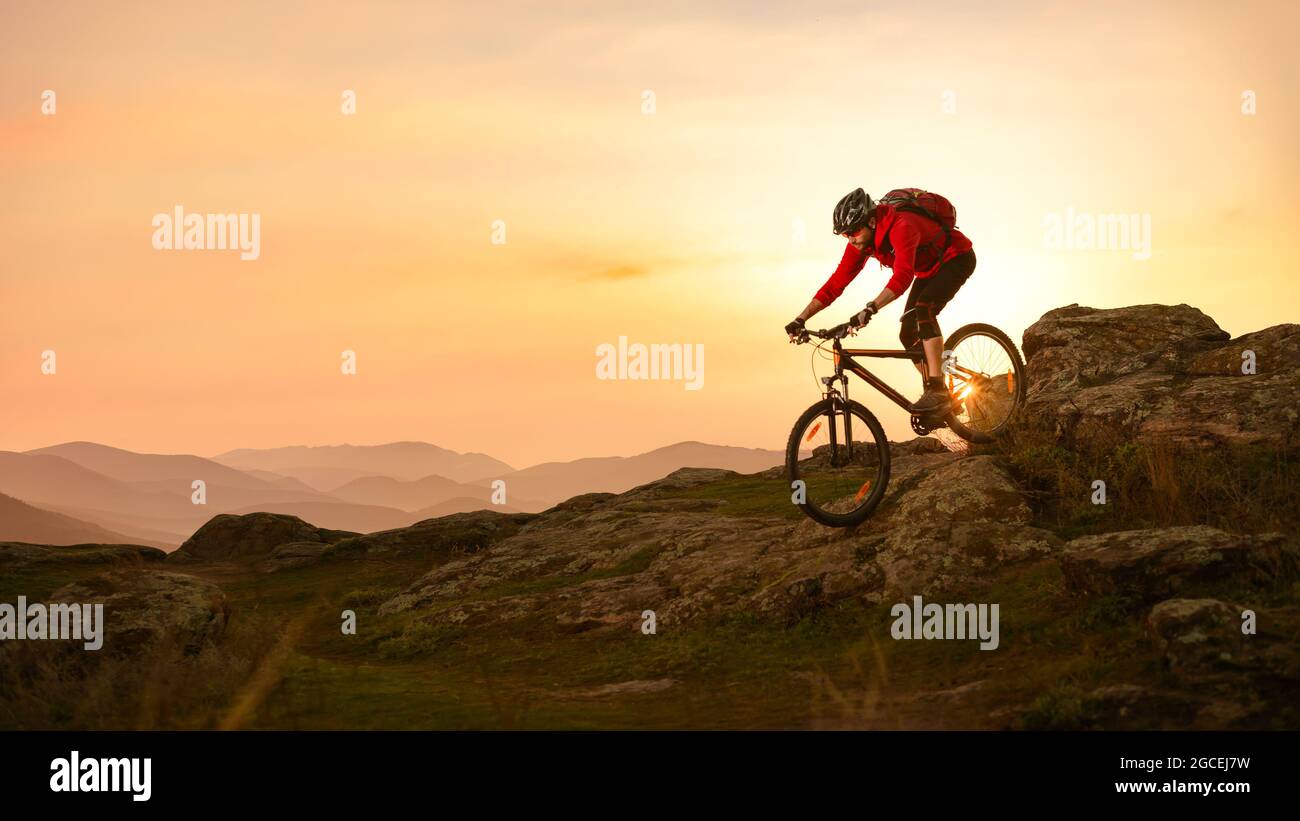 Radler in Red Riding Bike auf dem Sommer Rocky Trail bei Sonnenuntergang. Extreme Sport und Enduro Biking Konzept. Stockfoto