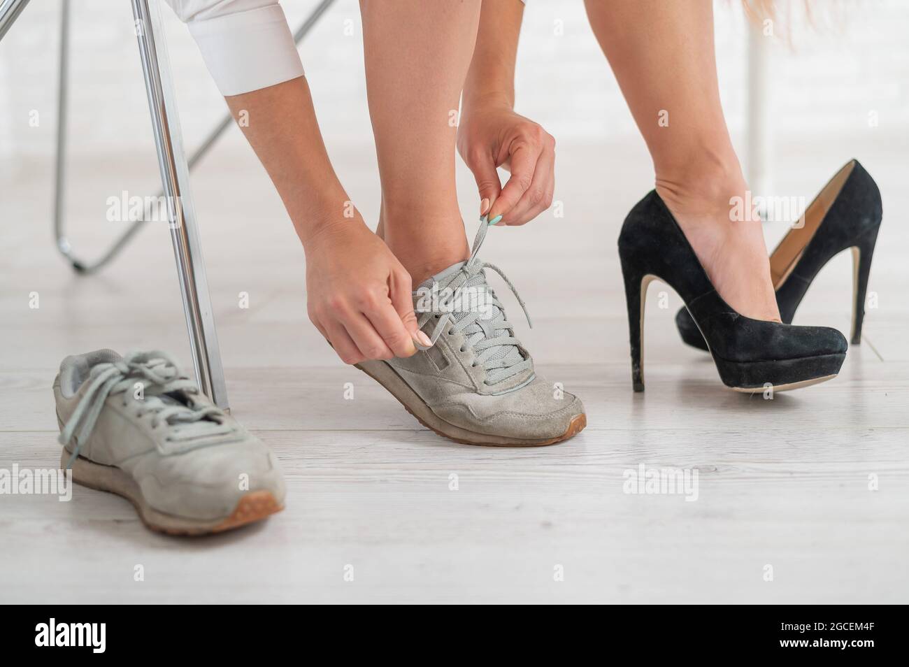 Nahaufnahme einer Geschäftsfrau, die schwarze Schuhe mit hohem Absatz  auszieht und sich in bequeme Sneaker verwandelt Stockfotografie - Alamy