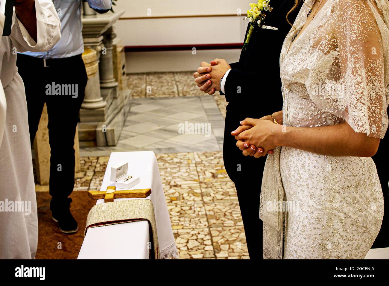 Hände der Braut und des Bräutigams vor dem Altar in einer katholischen Kirche. Hochzeitsprozess. Stockfoto