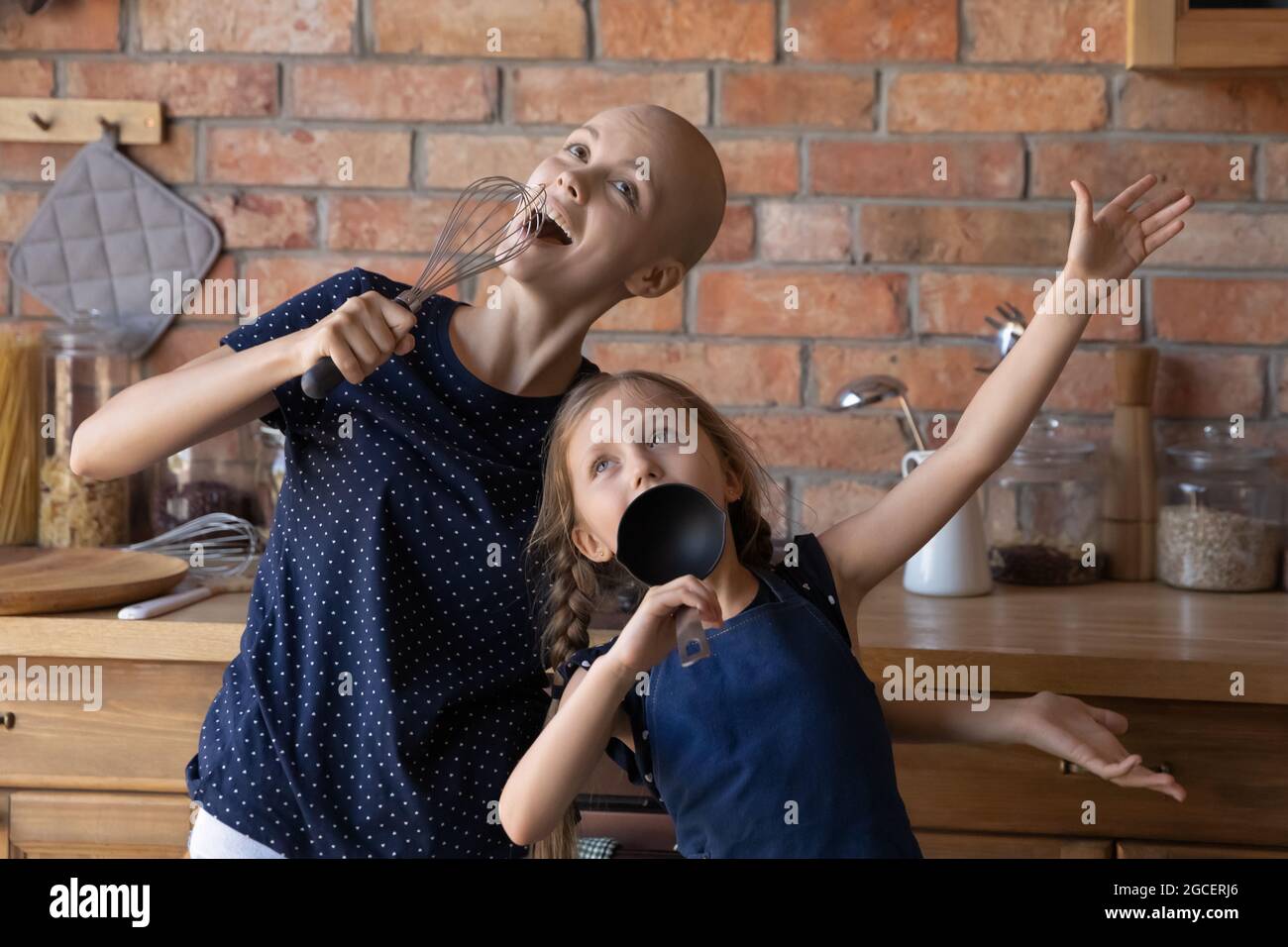 Aufgeregte Krebs-Mutter und lustige kleine Tochter spielen Konzert Stockfoto