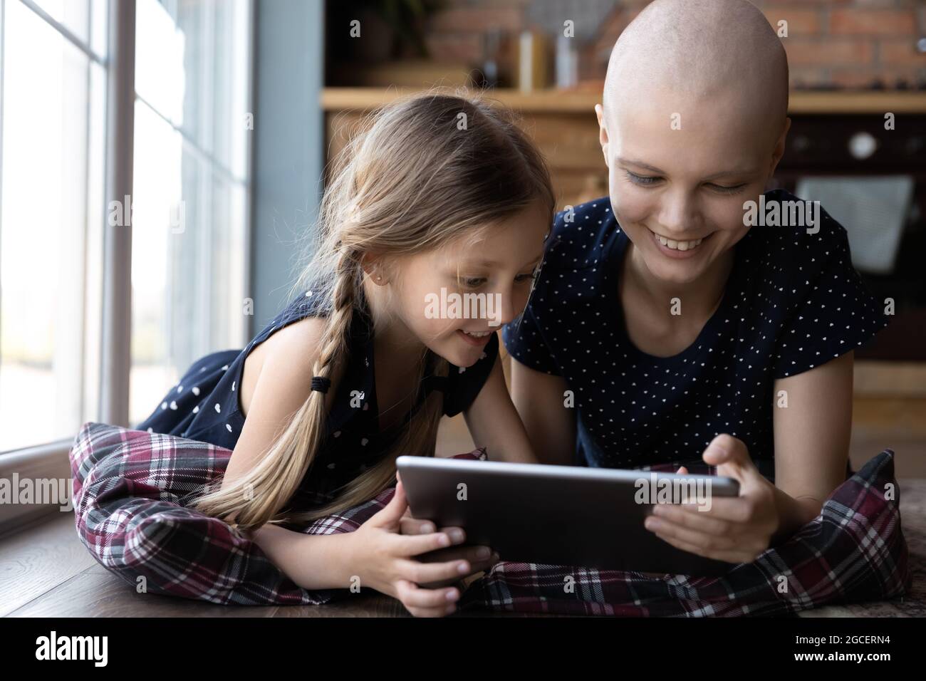 Glückliche kleine Tochter Kind und haarlose Krebs Mutter mit Tablette Stockfoto