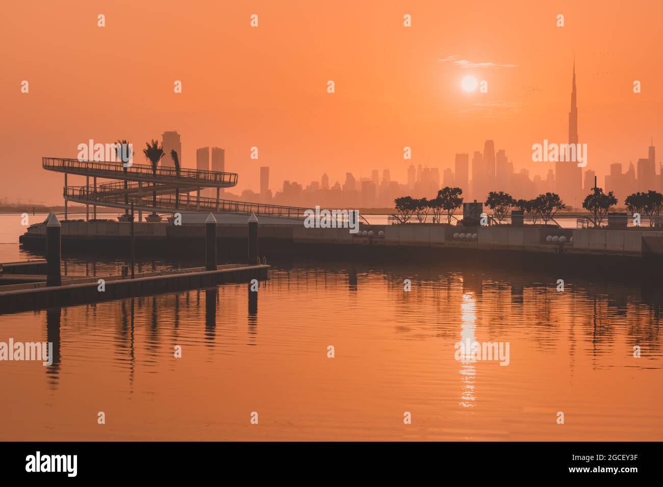 Dubai Creek Marina District bei Sonnenuntergang mit Blick auf den berühmten Burj Khalifa Turm und andere Wolkenkratzer auf der anderen Seite des Kanals. Stockfoto