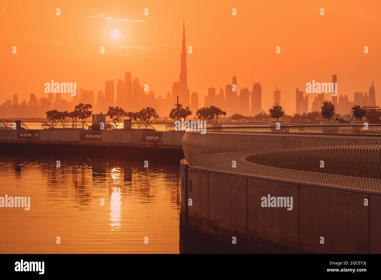 Dubai Creek Marina District bei Sonnenuntergang mit Blick auf den berühmten Burj Khalifa Turm und andere Wolkenkratzer auf der anderen Seite des Kanals. Stockfoto