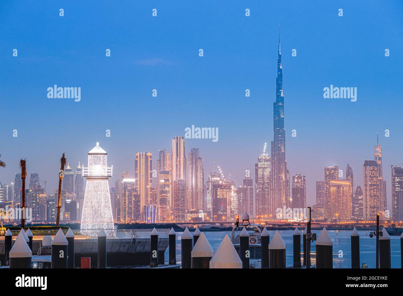 Beleuchteter dekorativer Leuchtturm im Hintergrund des berühmten Burj Khalifa Wolkenkratzers im Hafen von Dubai Creek Marina. Reisen und touristische Desti Stockfoto