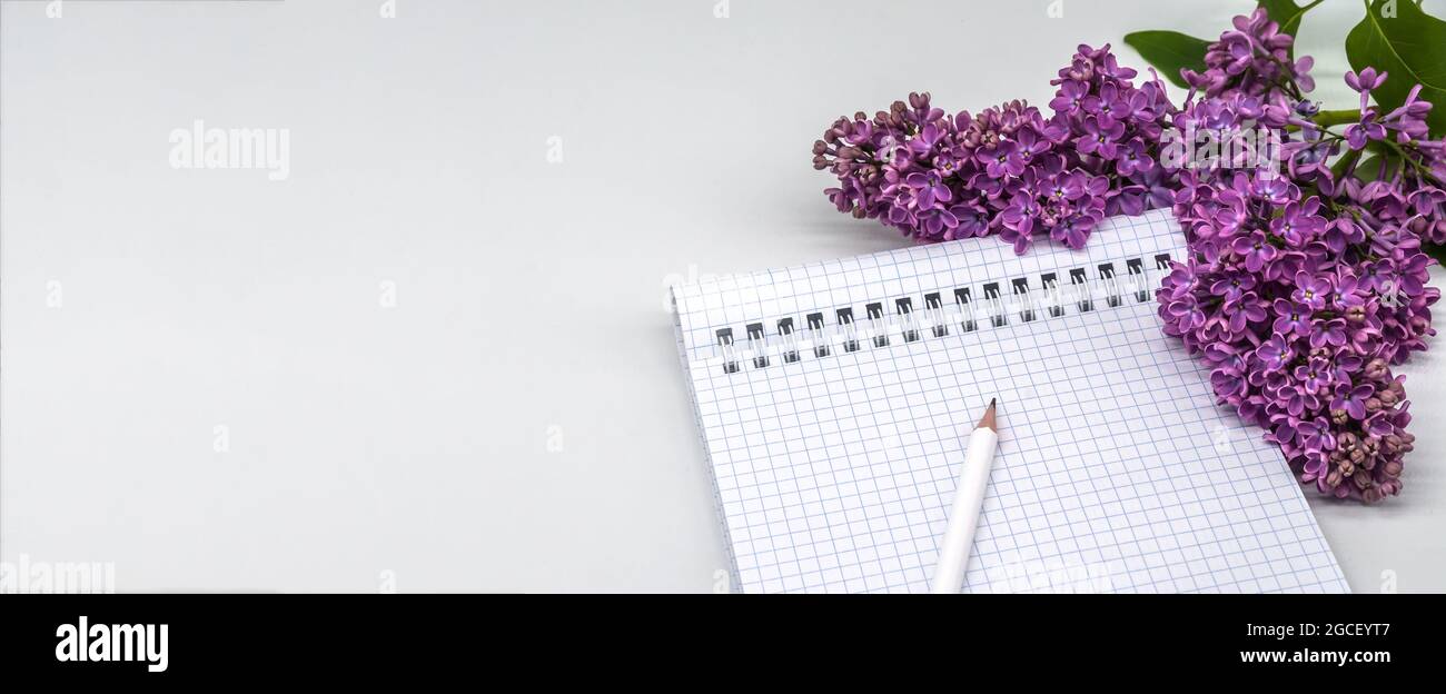 Notizblock mit Stift und Blumen. Spiralnotizbuch und Stift. Notebook-Flieder auf hellem Hintergrund. Stockfoto