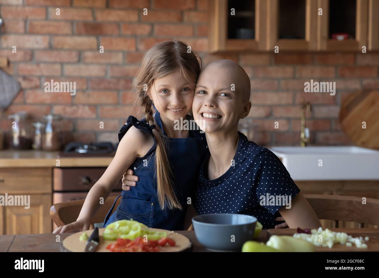Glückliches kleines Kind und haarlose Mutter kochen Mittagessen in der Küche Stockfoto