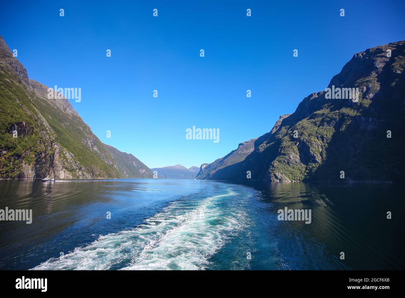 Wachen Sie vom Schiff auf, während Sie den Geiranger Fjord entlang fahren. Schöne Landschaft mit Klippen und Reflexen der Berge im Wasser, Norwegen. Stockfoto