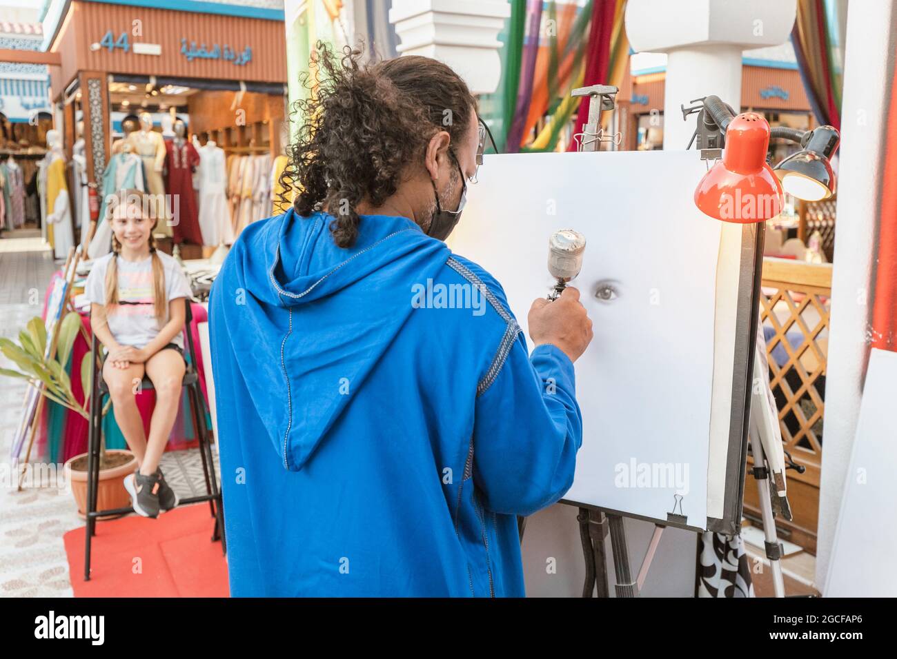 26. Februar 2021, VAE, Dubai: Ein Straßenkünstler malt seinen Kunden mit einer Airbrush auf Leinwand Stockfoto